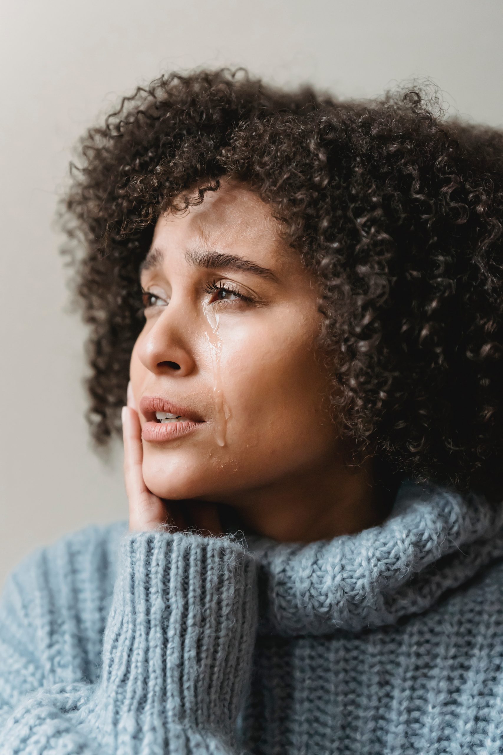 Image of woman looking into the distance with a tear on her cheek