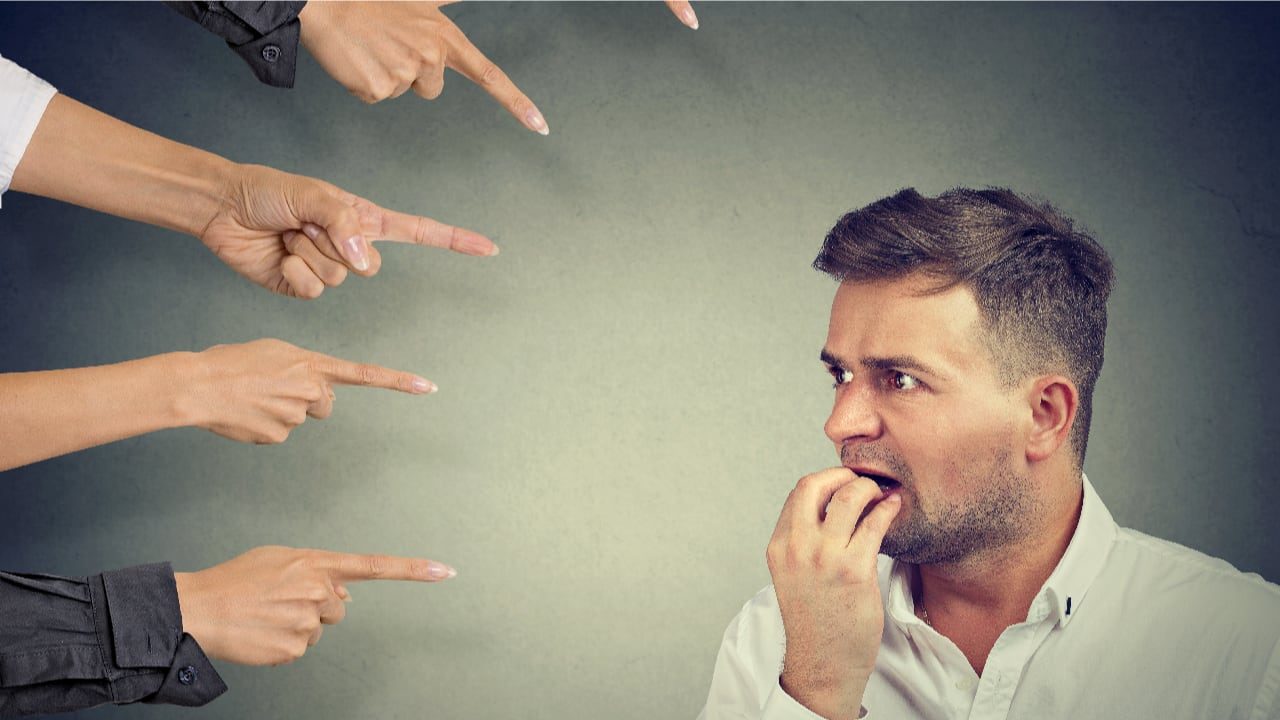 image of man looking anxious whilst hands point at him